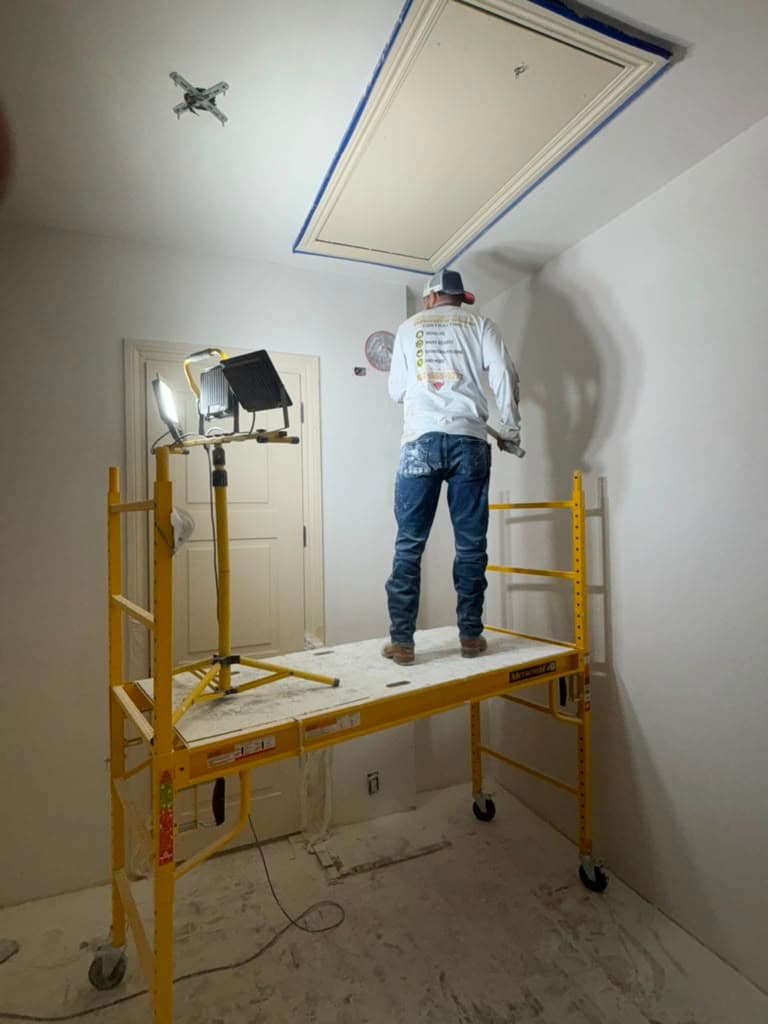 Crew member on scaffolding documenting ceiling damage during a San Antonio restoration