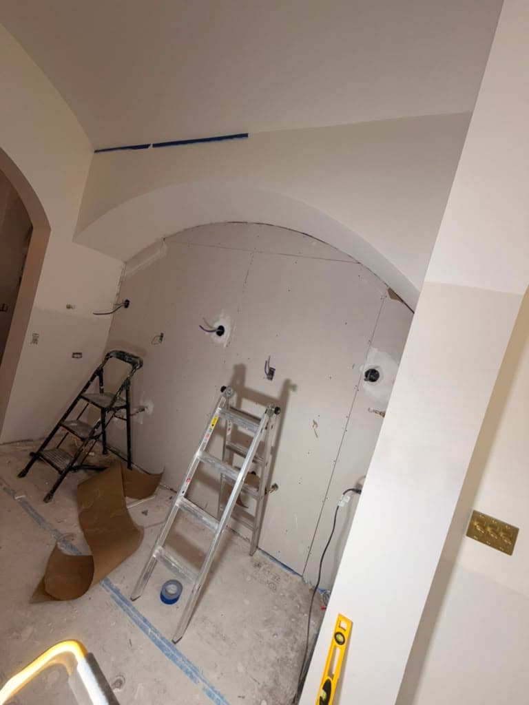 New drywall installed on an archway during water-damage reconstruction, floors protected, by Raging Bull Contracting, San Antonio