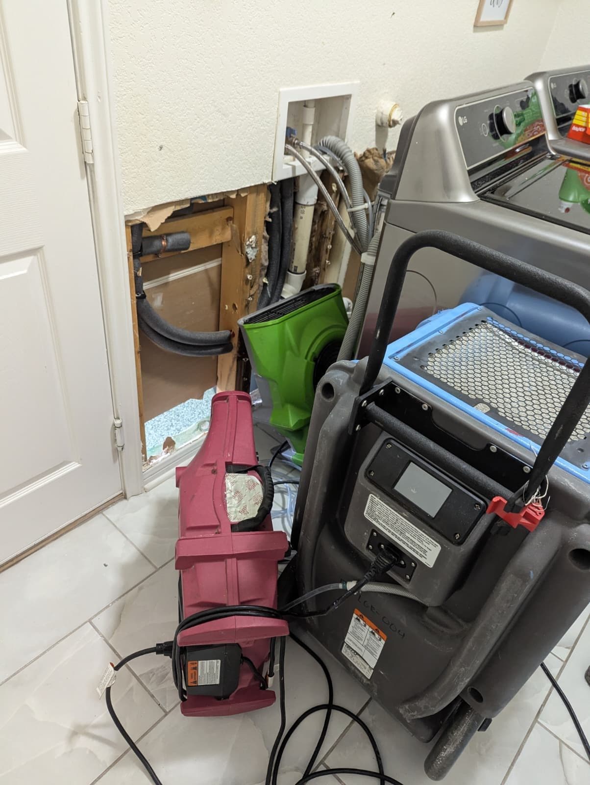 Air movers and an LGR dehumidifier running at the opened laundry wall in a Cibolo home