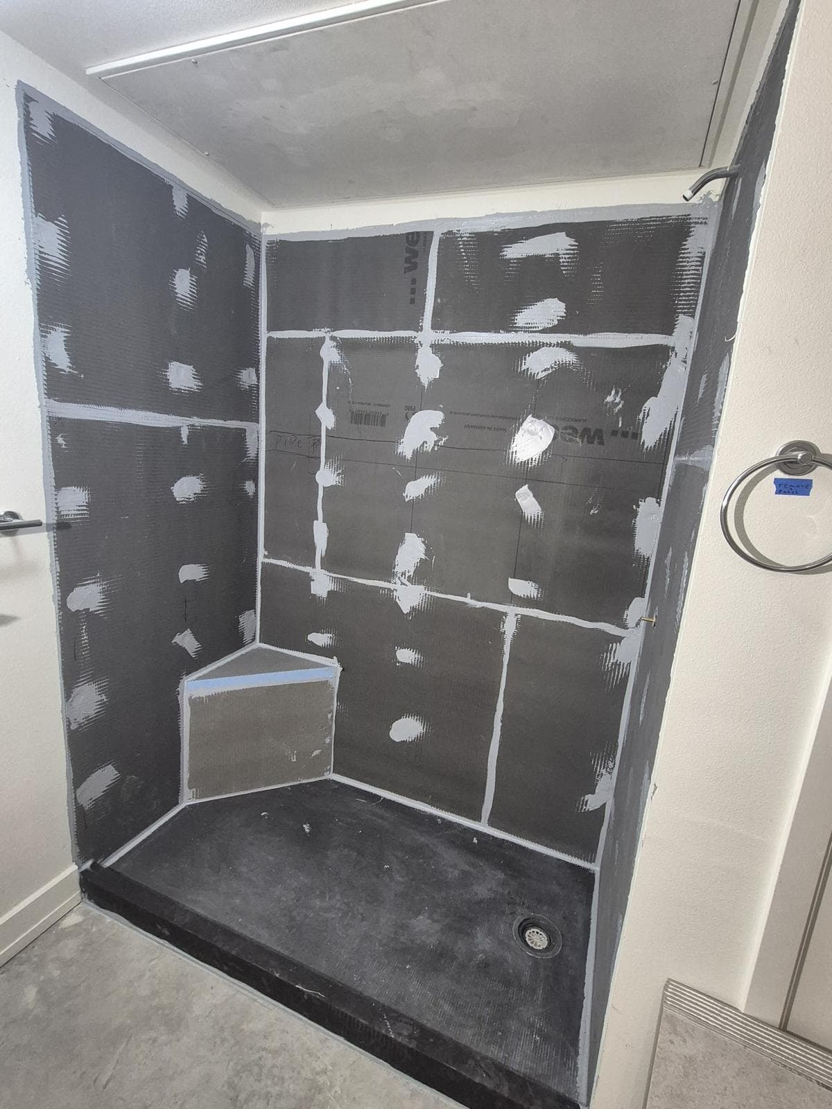 wedi board shower walls with every seam and fastener sealed, a boarded corner bench, and a bonded wedi Fundo base with an offset drain, before tile, in a downtown San Antonio bathroom